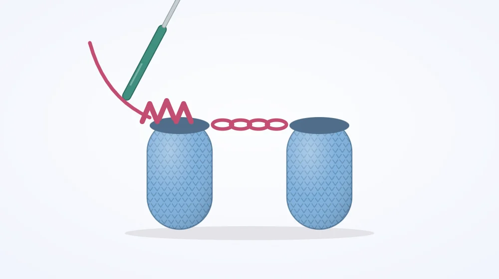 Two short crocheted leg tubes standing side by side, connected at the top by a short chain bridge, with a crochet hook beginning the first body round around both