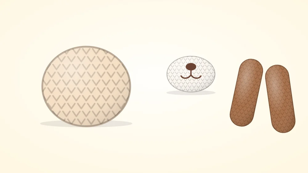 Oval crocheted muzzle with an embroidered nose and two long floppy brown ears lying next to a bare cream head