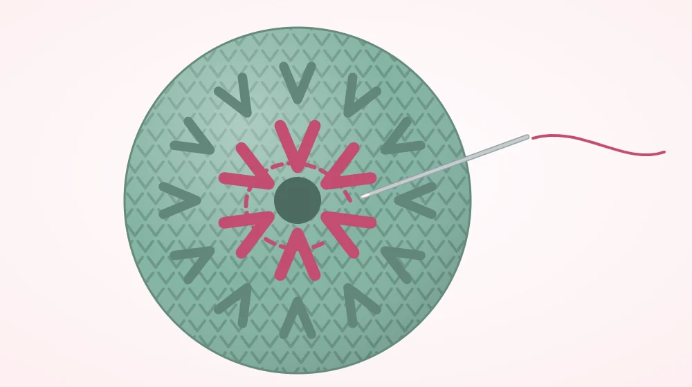 Close view of the last round of a crocheted ball with a yarn needle passing through the front loops of the final six stitches to draw the hole closed